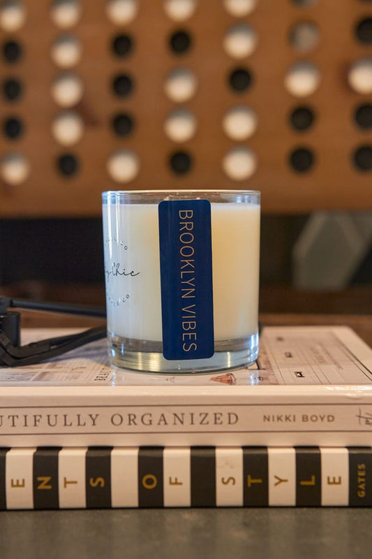 Candle labeled 'Brooklyn Vibes' on top of books with a blurred background