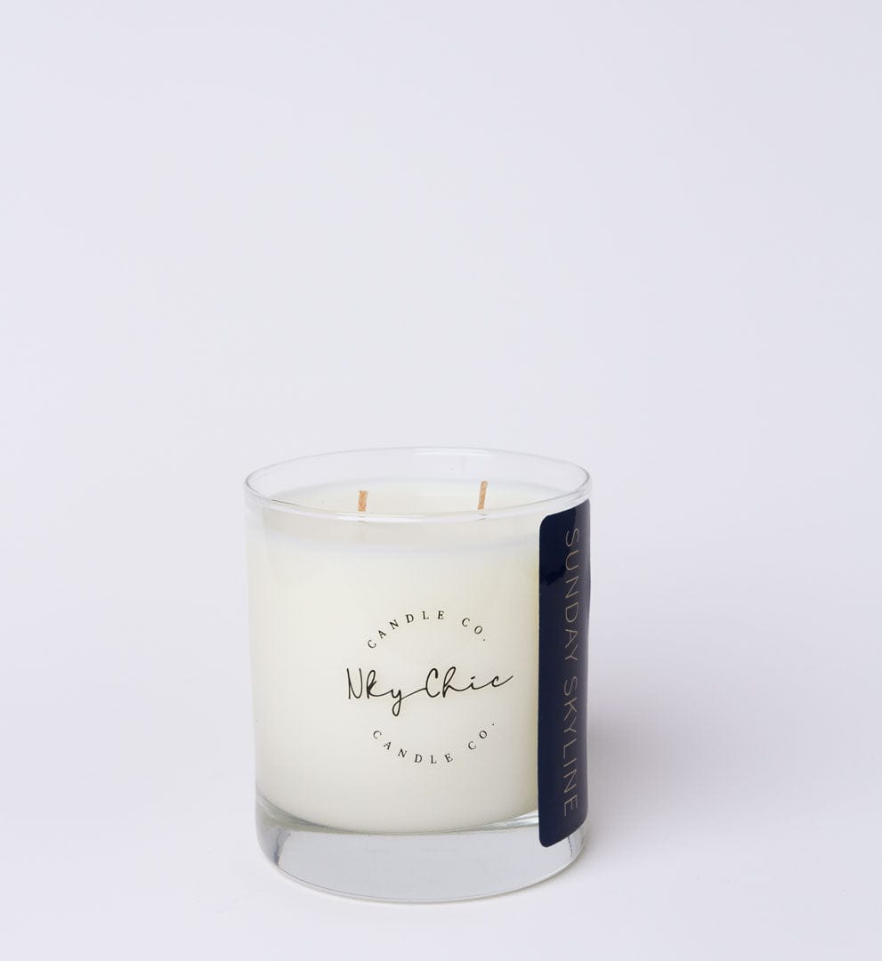 White candle in a glass jar with a black label on a white background